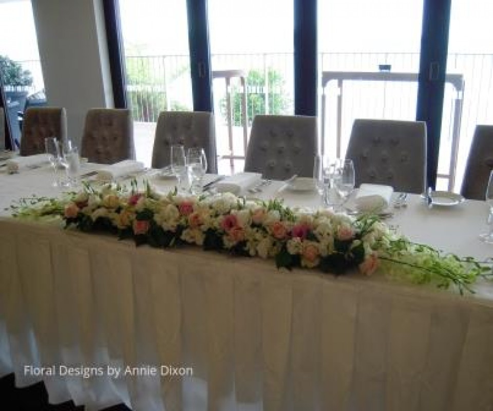 Pink and white arrangement or Roses Singapore Orchids and along front edge of bridal table