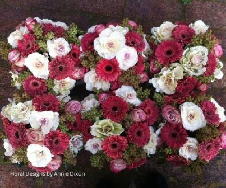 Overhead view of table arrangements including gerberas, kale, roses and brezillia
