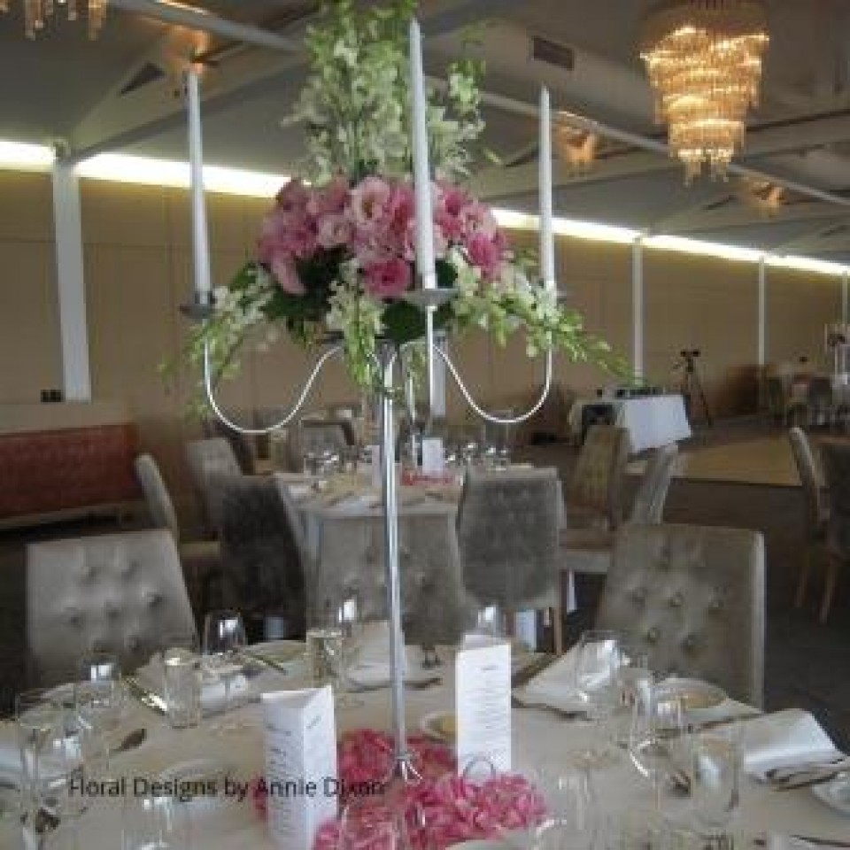 Silver candelabra arrangement of Lisianthus and Singapore Orchids with Rose petals around base
