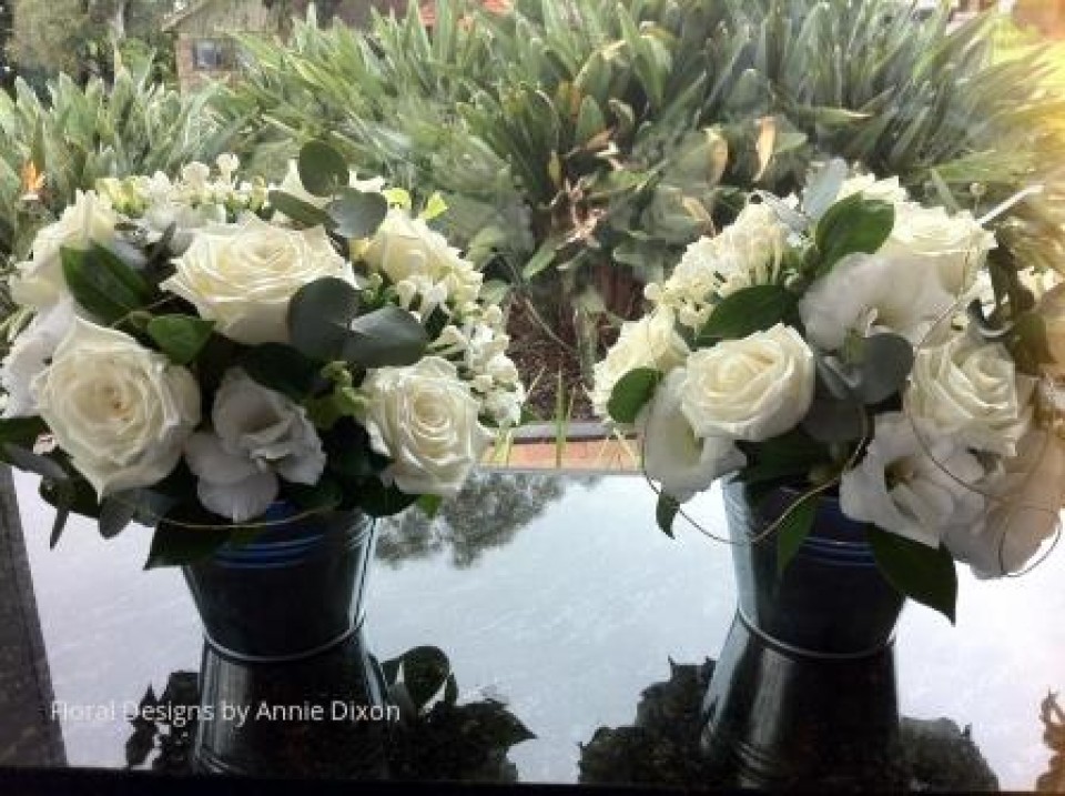 Two small bucket arrangements of ivory roses entwined with gold thread