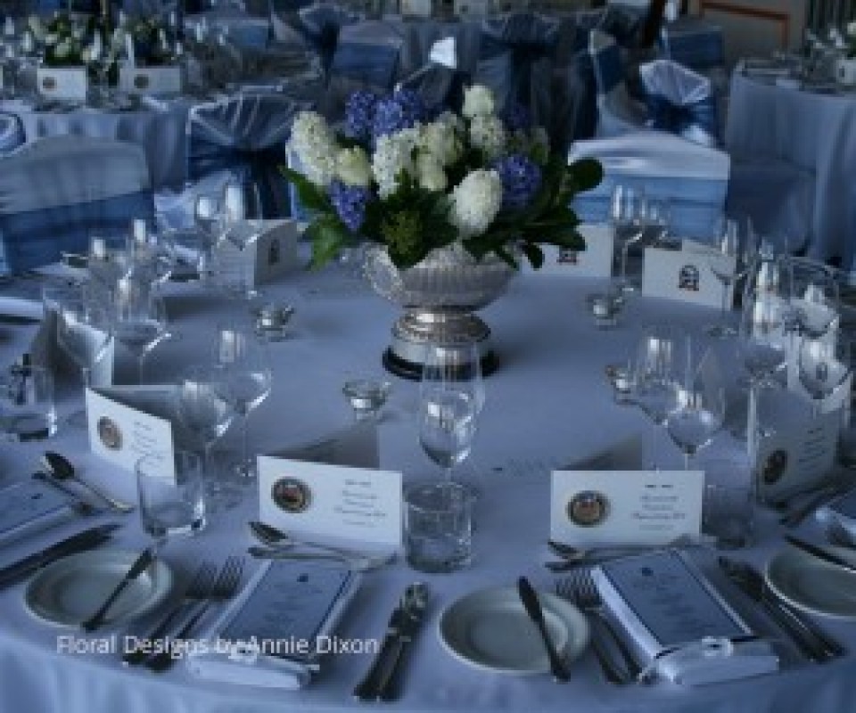Corporate table arrangement of blue Hyacinths and white Roses in silver trophy