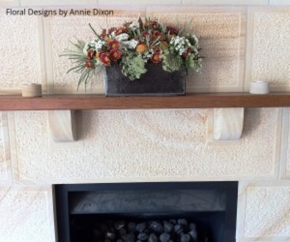 Cottage floral arrangement on wooden mantle over sandstone fireplace