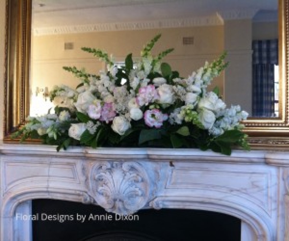 Traditional arrangement of pastal pink flowers on marble mantle