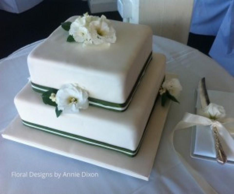 2 tier square wedding cakedecorated with white Lisianthus and green and white ribbon