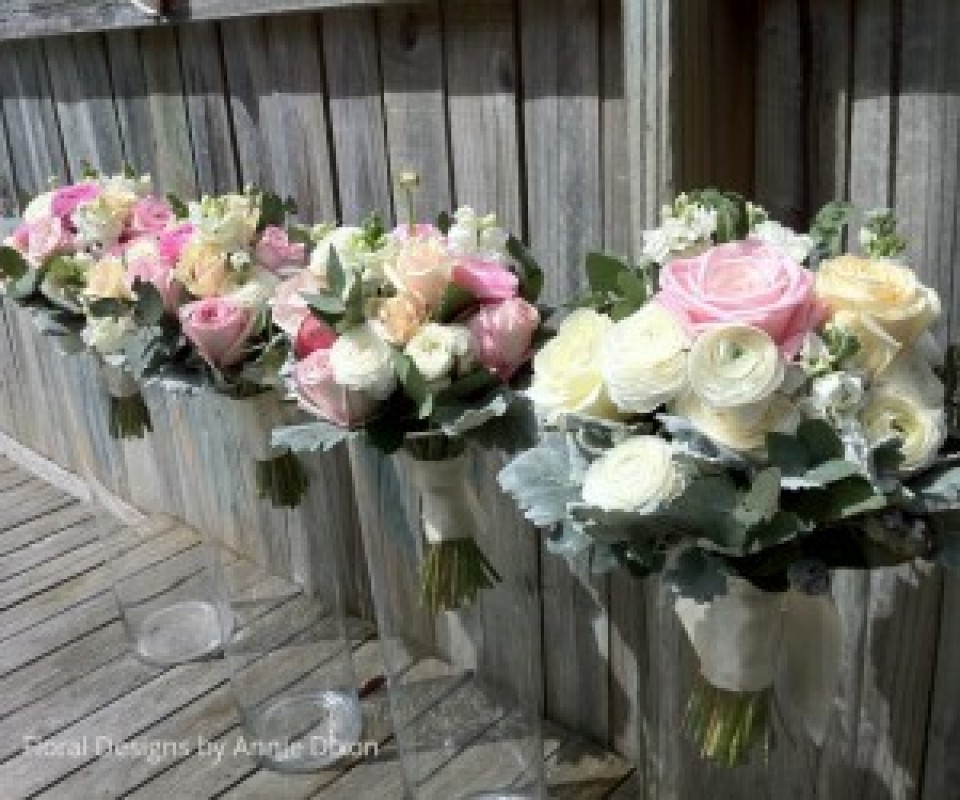 Bride and bridesmaids' posies of mixed pastal spring flowers including ranunculus and roses