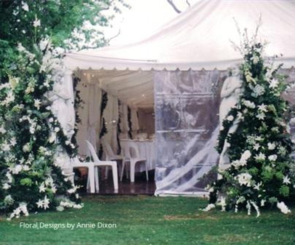 Garden statues decorated with flowers at entrance to wedding marquee