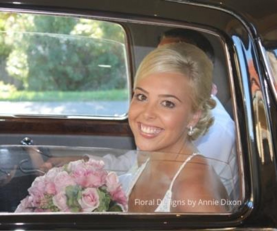 Bride and her pink bouquet inside the wedding car